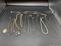 Wide view showing 10 necklaces of various gold and silver colored chains including heart pendant and thin chain styles.