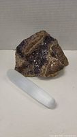 Amethyst cluster and selenite wand next to each other on a white surface showing size and texture details
