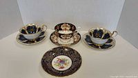 Full set of 3 decorated porcelain cups each with matching saucers and 1 additional decorated saucer