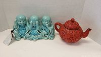 Blue ceramic triple Buddha figure set against a white backdrop with tag attached.