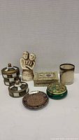 Overall lot showing five decorative boxes and one small couple figurine with white background.