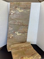 Full view of the folded gold coloured long table runner showing floral botanical pattern with gold accents.