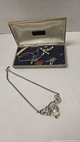 Two crystal necklaces and a pair of matching earrings displayed in a vintage Trifari box with satin and velvet interior.