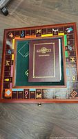 Overhead view of wood framed Monopoly board with binder placed on top