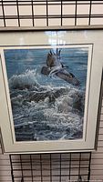 Framed print showing osprey flying over the ocean waves in naturalistic style with blue and grey tones.