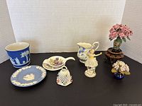 Full view of all small china and decorative items including 2 Wedgewood, Royal Albert creamer, fairy figurine, tea bag set, and floral decorations.