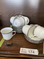 Set of 8 white bone china cups stacked on matching saucers, showing the full set and overall condition.