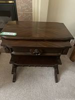Front view of the larger nesting table showing wood grain, false drawer with decorative handle, and fixed shelf.