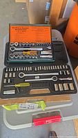 Open case showing 28 piece socket wrench set with chrome vanadium steel tools and orange label inside lid listing contents.