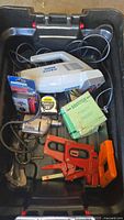 View of the lot from above showing Hoover vacuum, staplers, drill, multimeter, and tape measure inside a large black Rubbermaid tote