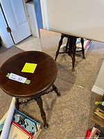 Wooden round piano stool and square mirror placed on floor near wall.