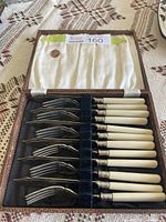 Full view of the vintage fish serving set in a brown case with velvet and satin lining, containing six forks with ivory handles.