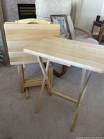 Three wooden TV tray tables with foldable legs displayed standing and one table set up.