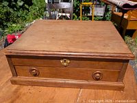 Top and front view of a cherry wood lap desk with one drawer, wooden knobs, and brass keyhole escutcheon.