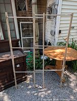 Full view of the early wooden horizontal drying rack outdoors showing its structure and height relative to nearby objects.