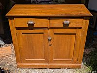 Front view of early pine buffet showing two drawers with metal cup pulls and two paneled doors with latch.
