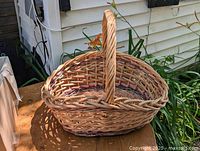 Front angle showing the overall shape, handle, and weave detail of the wicker basket.