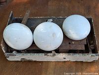 Photo of old metal door lockset with three white porcelain knobs showing the lock mechanism and condition