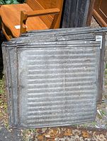 Lot of 10 vintage galvanized tin ceiling or roof tiles stacked together outdoors, showing front face with ridged texture and weathered metal surface.