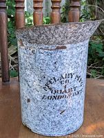 Front side view of vintage grey graniteware jug showing company logo and rust spots.