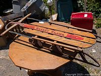 Photo showing full wooden sled positioned on wooden table, highlighting Rocket Plane graphic and sled structure.