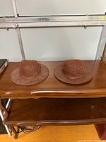 Two brown leather wide-brim hats on table, top view