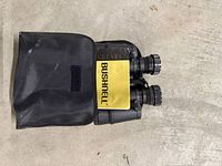 Bushnell binoculars partially inside black case showing yellow Bushnell label