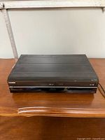 Front and top view of Toshiba dual-tray DVD CD player on wooden surface