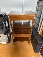 Both matching wooden two-tier end tables stacked for storage
