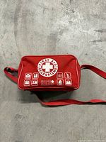 Front view of red Safe & Sound first aid bag showing emblem and strap