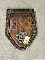 Front view closed showing wood panel, metal frame, leaf accent, sprocket ring and retail tag