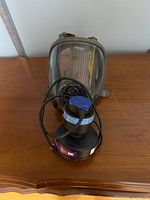 Front view showing full face mask, clear visor, 3M filter canister, attached cable