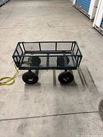 Side view of green metal mesh utility wagon with four pneumatic tires