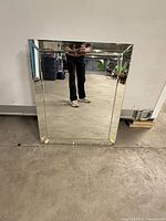 Front view of rectangular frameless mirrored medicine cabinet leaning against wall