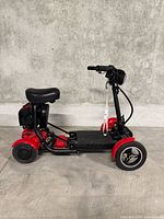Side view of red three-wheel mobility scooter with seat and battery bag