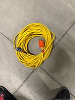 Yellow extension cord with orange male plug and blue female connector coiled on floor
