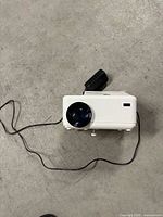 Front view of white projector with lens and cord