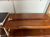 Full view of wooden cane on table showing overall length and shaft carving
