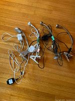 Four clamp-on accent lamps with various clips and attached cords and power adapters photographed on wood floor.