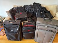Image of assorted luggage items on a sofa including suitcases, backpacks, suit bags, and duffel bags