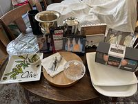 Table with various entertainment and serving items including buckets, platters, drinkware, boards, and utensils