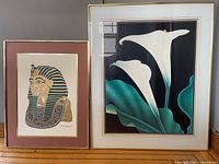 Two framed prints side by side: Egyptian pharaoh head and white calla lilies.