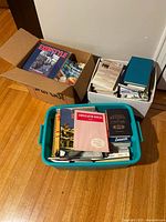Photo showing three boxes filled with various books. Titles visible include 'Conversation Manual' and 'Learn Spanish the Easy Way'.