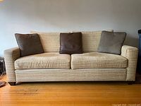 Front view of the maize-colored Upholstery Arts custom sofa with three coordinating pillows (two fabric, one leather)
