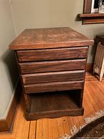 Image of octagonal wood storage base with three drawers in front, showing wood grain and signs of wear.