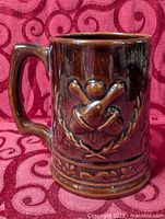 full left profile of mug showing handle and relief design