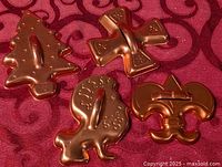 All four copper-tone cookie cutters on fabric background