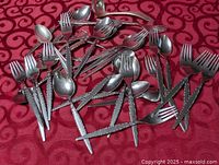 Group shot of stainless forks, spoons, sporks, ladle on red cloth