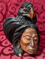 Front three-quarter view of carved wood eagle and First Nations elder sculpture