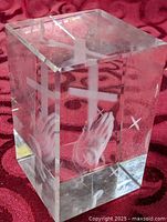 Full view of clear glass block showing etched cross and praying hands